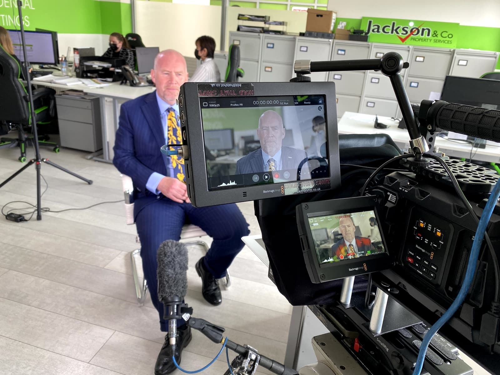 An estate agency director interviewed in his office, with the camera monitor in the foreground