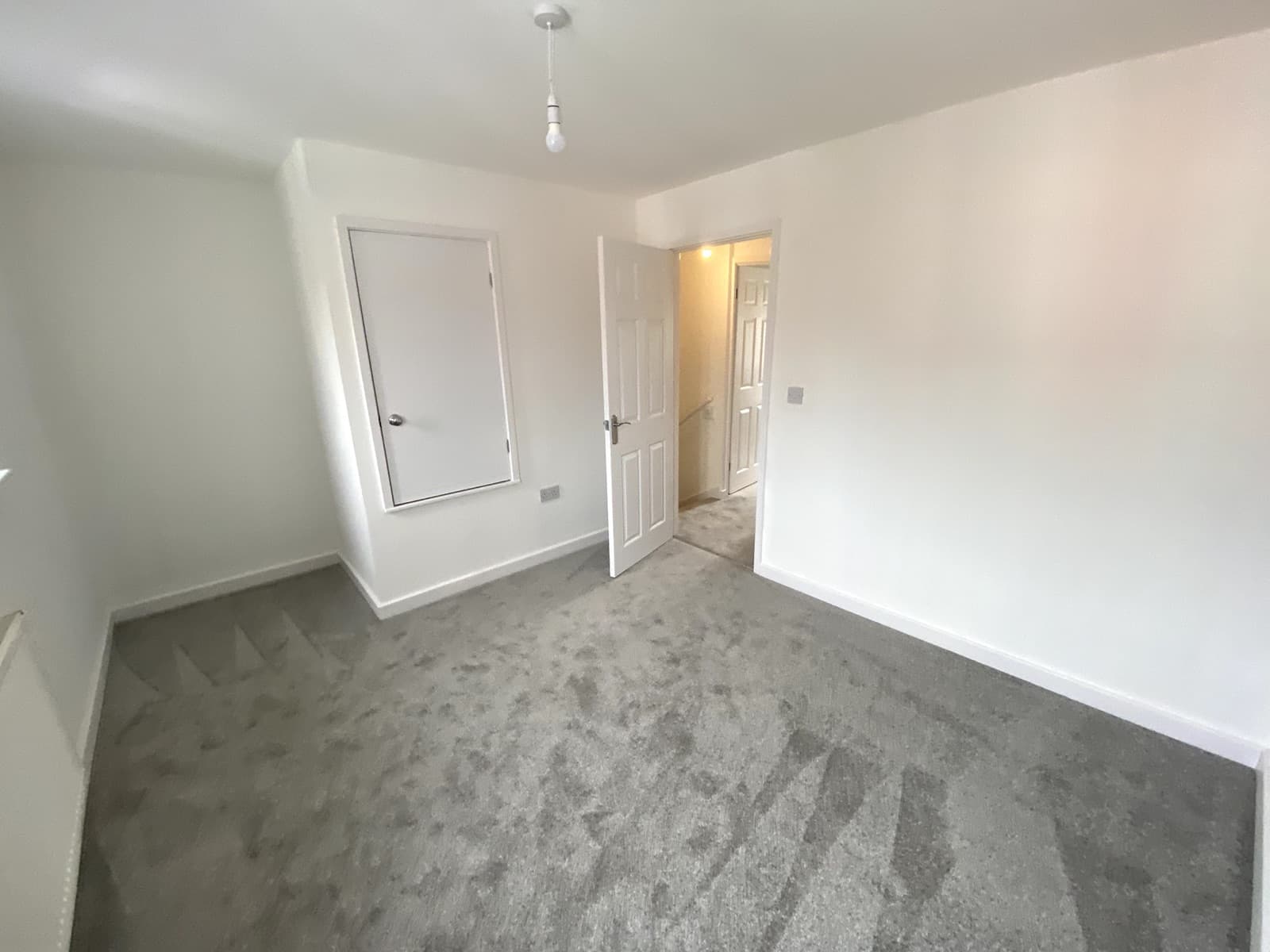 An empty, freshly decorated living room with new grey carpet