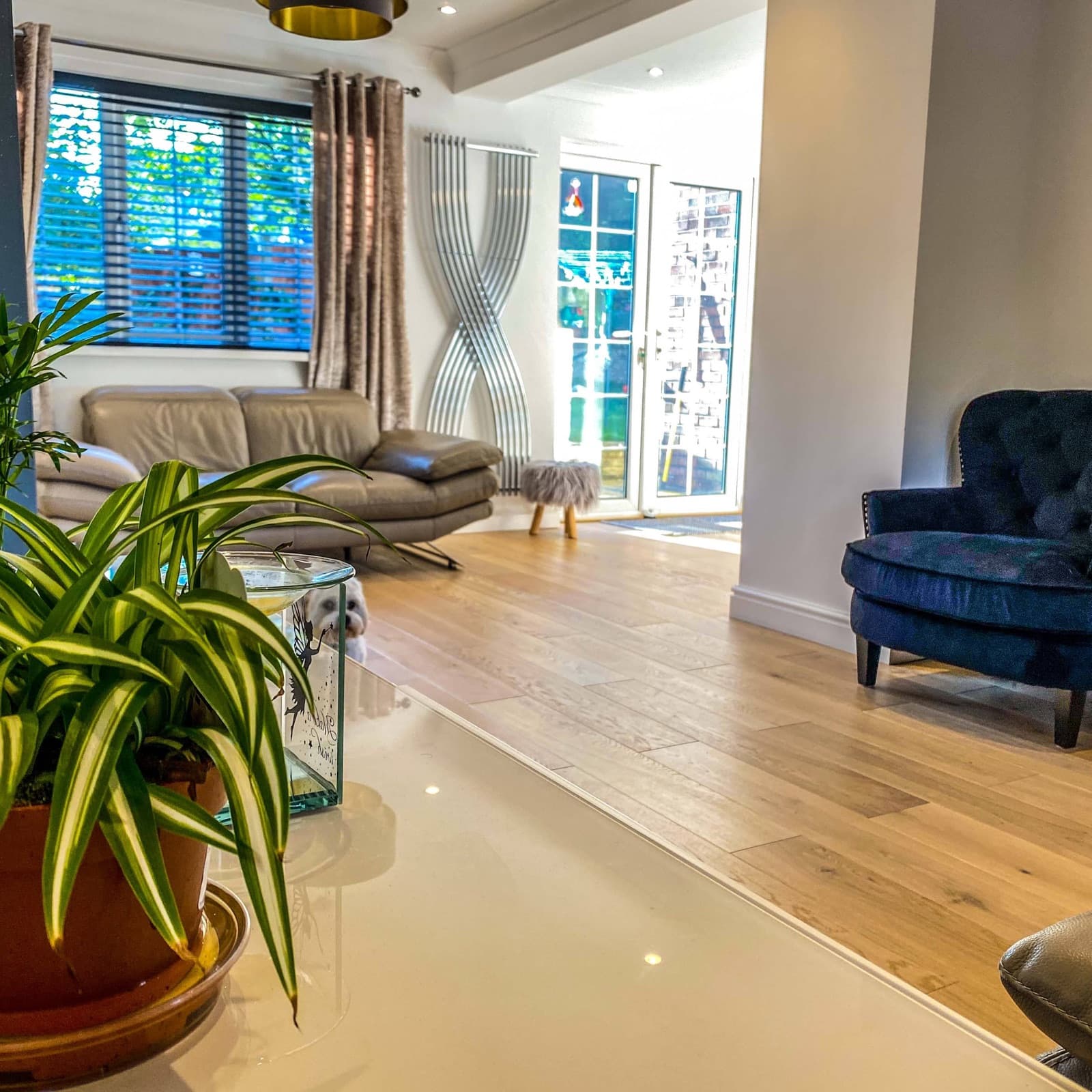 A living room with oak floors, a blue velvet armchair and French doors to the garden